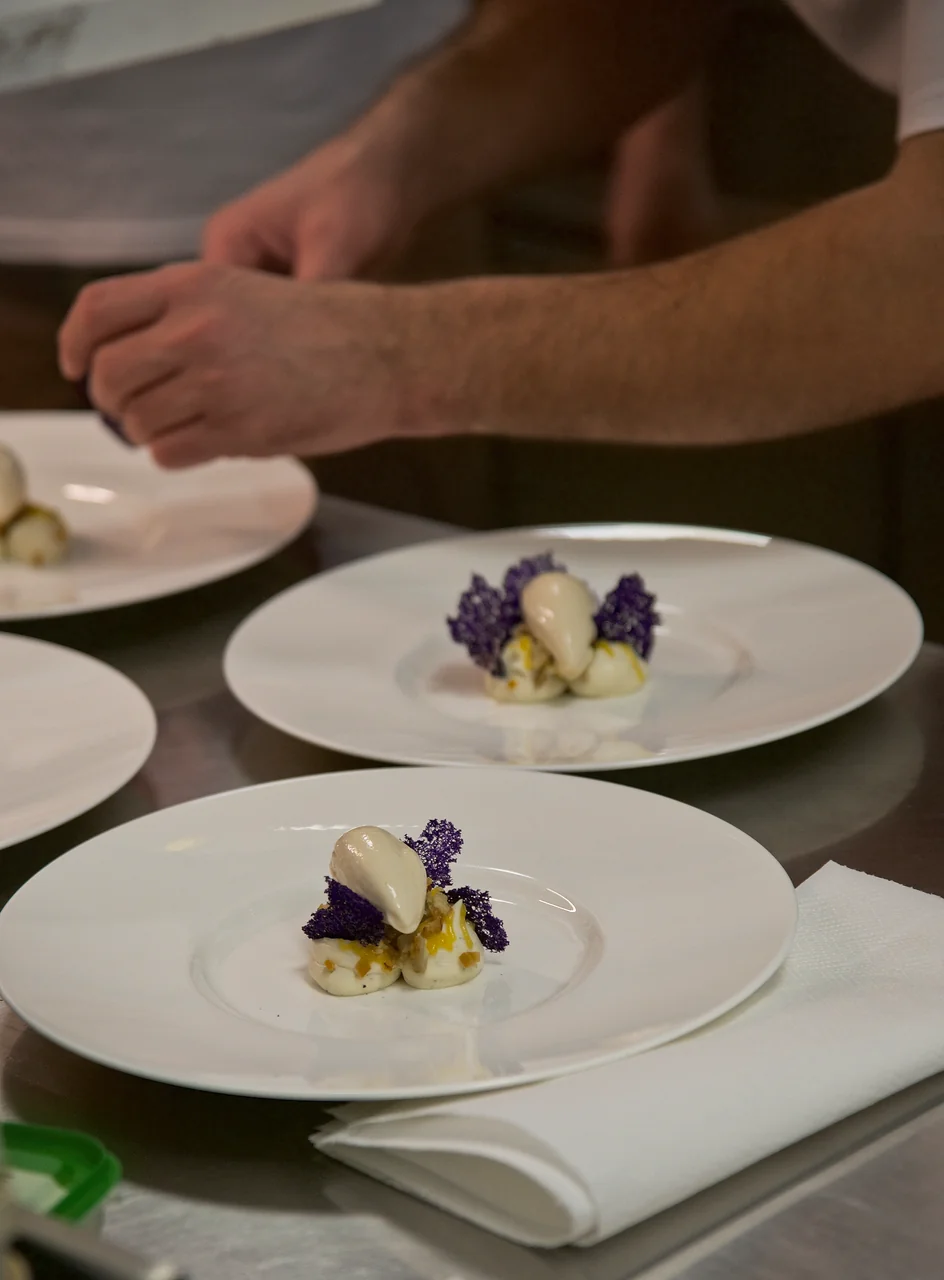 Culinary chef artfully preparing and plating delicate gourmet course in professional kitchen