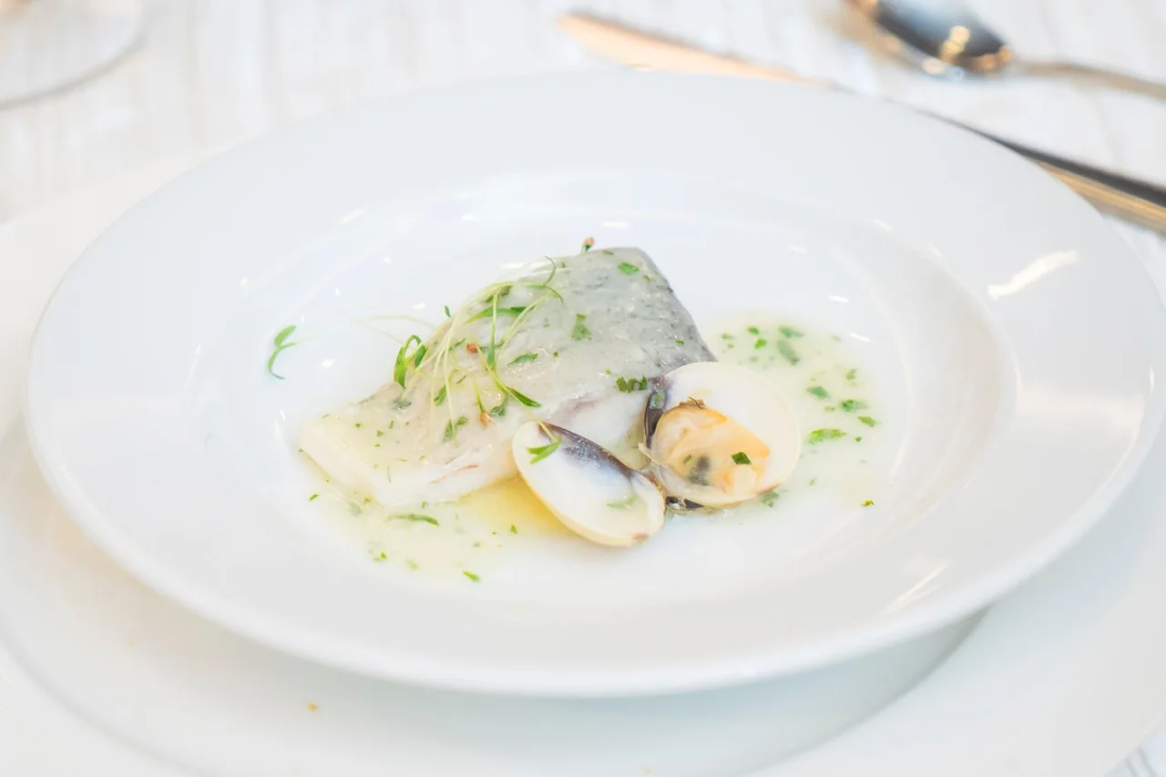 Artistic seafood presentation with broth and garden herbs