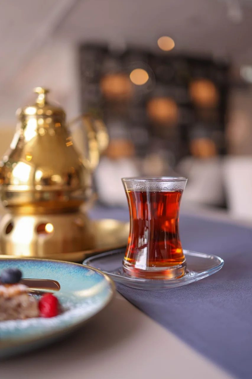 Steeping herbal tea in a fine glass saucer beside delicate pastry