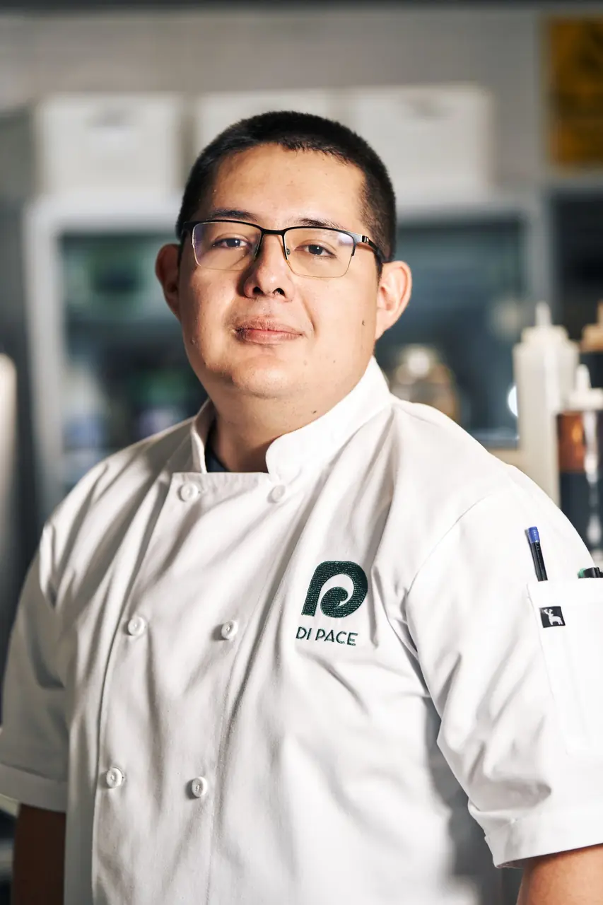 Head chef standing poised in pristine professional culinary kitchen of Zelvari Cuisine Hall