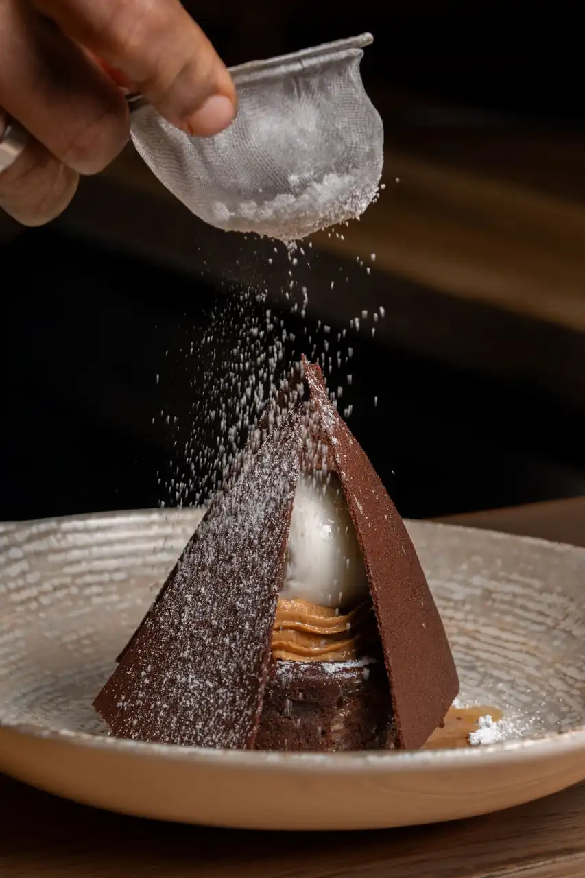 Close-up of a delicate artisan chocolate confection dusted with sugar for evening banquets